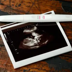 USG pokazuje, jak wygląda płód w 7 tygodniu ciąży. Obok leży pozytywny test ciążowy.