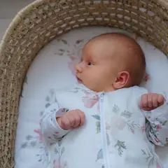 Malutkie dziecko w śpiworku z motywem kwiatowym, leżące w wiklinowym koszu. Od kiedy kołderka dla niemowlaka jest tak urocza?