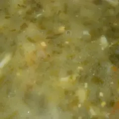 Zielona, kremowa zupa szpinakowa dla niemowlaka, z kawałkami jajka i marchewki.