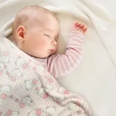 Śpiące dziecko otulone kocykiem w misie. Idealne wymiary kocyka dla niemowlaka zapewnią komfortowy sen.