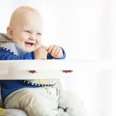 Uśmiechnięty niemowlak w krzesełku, gotowy na pyszny kefir dla niemowlaka.