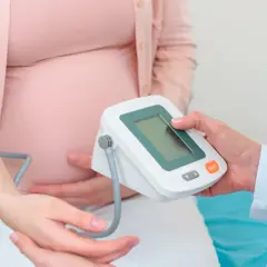 Kobieta w 14 tygodniu ciąży ma mierzone ciśnienie. Lekarz kontroluje jej zdrowie.
