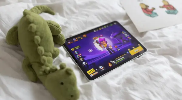 Pluszak-krokodyl obok tabletu z grą Brawl Stars. Zastanawiasz się, brawl stars od ilu lat jest dostępne?