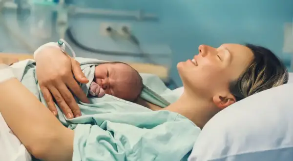 Szczęśliwa mama tuli noworodka po porodzie. Skurcze w 36 tygodniu ciąży zakończyły się narodzinami maleństwa.