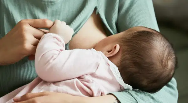 Mama karmi dziecko. Piersi są pełne mleka, co może powodować uczucie twardości przy karmieniu.
