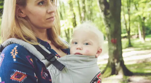 Mama z dzieckiem w nosidle w lesie. Zastanawiasz się, jakie nosidełko wybrać? To wygodne rozwiązanie na spacery.