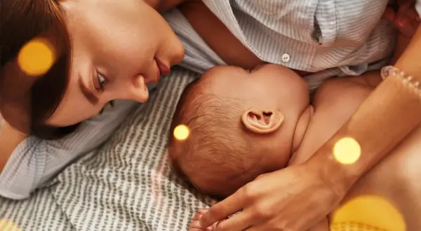 Mama czule patrzy na dziecko, które karmi piersią. Czasem pojawia się kryzys laktacyjny w 4 miesiącu, ale miłość i bliskość pomagają go pokonać.