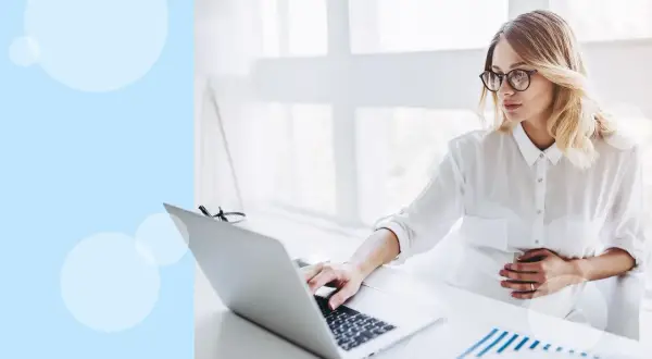 Kobieta w ciąży pracuje przy laptopie, dotykając brzucha. Zastanawia się, do którego miesiąca ciąży można pracować.