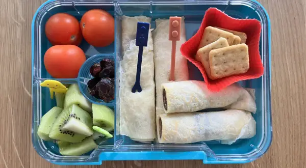 Kolorowe śniadaniówkowe pudełko dla dzieci: pomidorki, kiwi, suszone śliwki, naleśniki z czekoladą i ciasteczka. Idealne na drugie śniadanie!