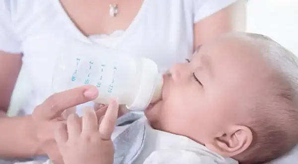 Mama karmi dziecko mlekiem z butelki. Dziecko powinno pić mleko, dopóki nie zacznie jeść stałych pokarmów.