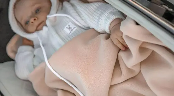 Niemowlę w wózku otulone beżowym śpiworkiem. Idealny na chłodniejsze dni, sprawdzi się od jakiej temperatury śpiworek do wózka.