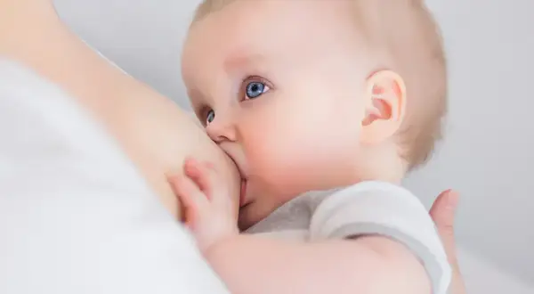 Niemowlę z niebieskimi oczami karmione piersią. Karmienie piersią może wpływać na objawy owulacji.