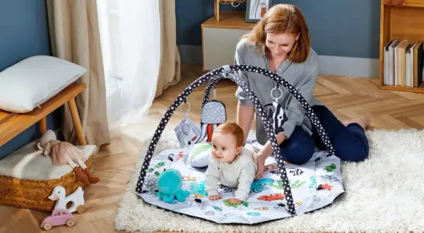 Mama bawi się z dzieckiem na macie edukacyjnej z motywem podwodnym. Idealna mata dla niemowlaka do rozwoju.