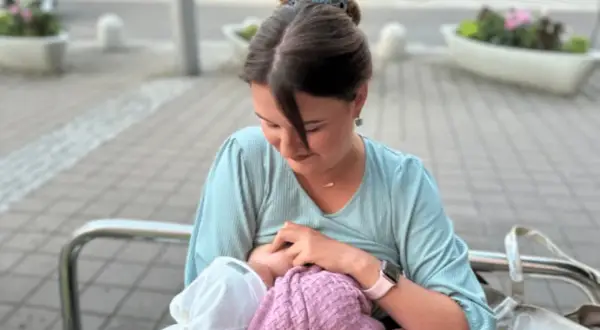 Mama karmi piersią dziecko na ławce w parku. Naturalne karmienie piersią w miejscu publicznym to piękny widok.