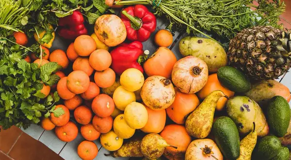 Kolorowe owoce i warzywa: pomarańcze, papryki, granaty, mango, awokado, gruszki, ananas, marchew, cytryny. Idealne, jakie warzywa jeść w ciąży.