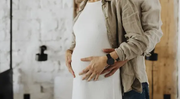 Para, obejmująca brzuch kobiety, czeka na dziecko. Po 16 dniach po porodzie można się kochać.
