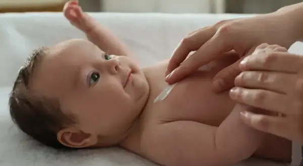 Delikatna pielęgnacja 2 miesięcznego dziecka. Kremowanie jego skóry to chwila bliskości i troski.