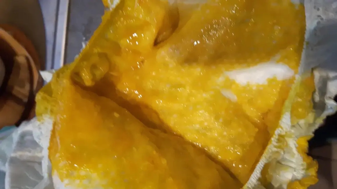 Jasnożółta, papkowata kupa po mleku modyfikowanym, z widocznymi grudkami, w pieluszce.