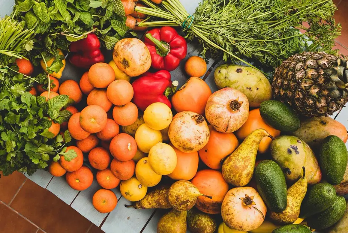 Kolorowe owoce i warzywa: pomarańcze, papryki, granaty, mango, awokado, gruszki, ananas, marchew, cytryny. Idealne, jakie warzywa jeść w ciąży.