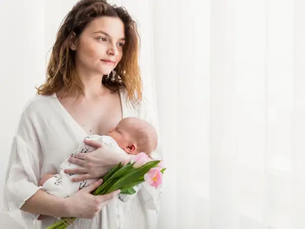 Mama tuli z dzieckiem na rękach, trzymając bukiet różowych tulipanów. To piękny obrazek z 4 trymestru.